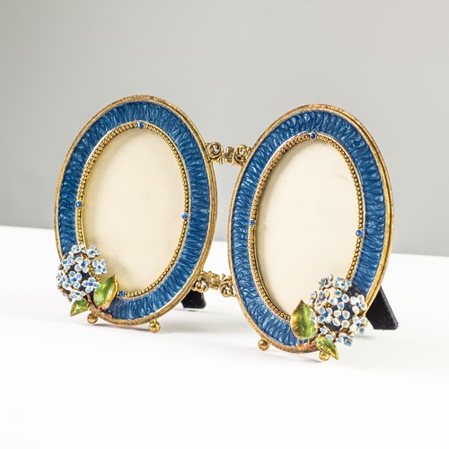 87 - GILT METAL AND BLUE ENAMELLED DIPTYCH PHOTOGRAPH FRAMES with blue glass 'jewel' decoration and appli... 