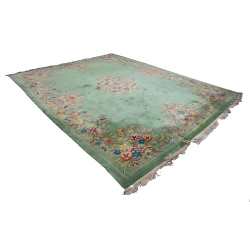 64 - LARGE EMBOSSED WASHED CHINESE CARPET, plain green field with large circular floral or foliate centre... 