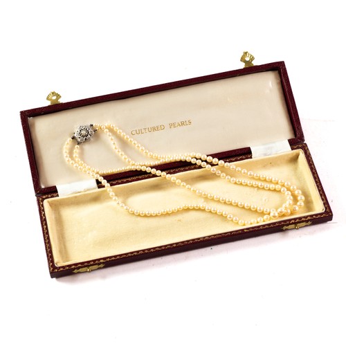 452 - BOXED CULTURED PEARL TWO STRING NECKLACE, each string graduated from the centre and with a pierced s... 