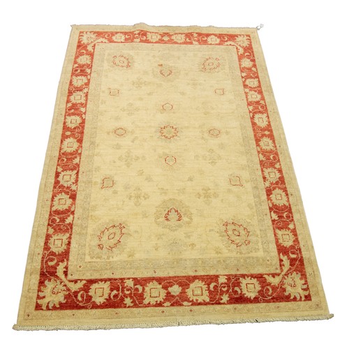 21 - INDIAN RUG with an all over beige formal floral pattern with red highlights, the principal border re... 