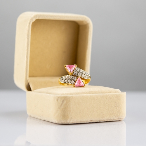 159 - GOLD COLOURED METAL CROSS-OVER RING, set with twenty small white stones and two triangular pink ston... 