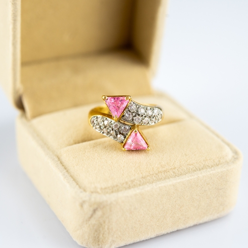 159 - GOLD COLOURED METAL CROSS-OVER RING, set with twenty small white stones and two triangular pink ston... 