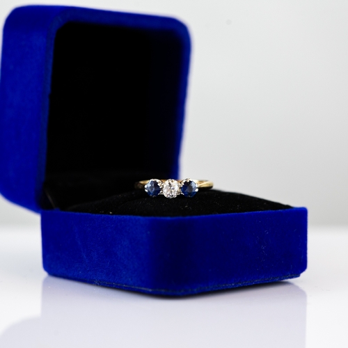 59 - 18ct GOLD AND PLATINUM RING, set with a centre round brilliant cut diamond, flanked by two round blu... 