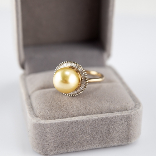 137 - 9k GOLD RING set with a centre large cultured pearl surmounting a radiating surround of small baguet... 