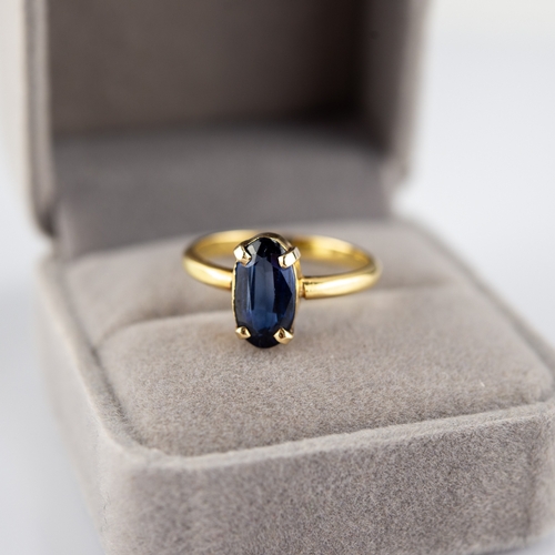 138 - 18ct GOLD RING with an oval synthetic sapphire in a four claw setting, 3.5gms, ring size 'P/Q'