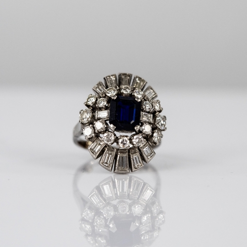 44 - PLATINUM, SAPPHIRE AND DIAMOND THREE TIER CLUSTER RING set with a centre emerald-cut blue sapphire, ... 