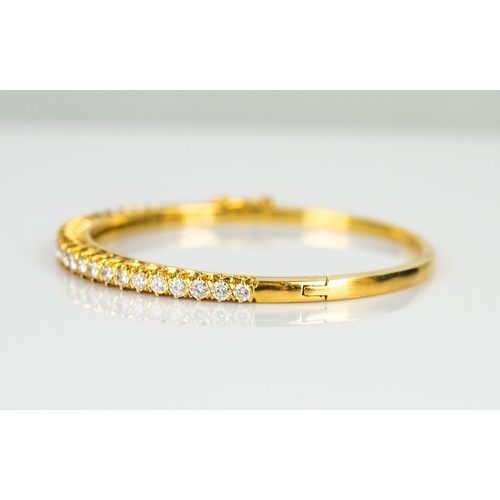 27 - GOLD AND DIAMOND HINGE-OPENING BANGLE, the top claw set with a half hoop of 26 round, brilliant cut ... 