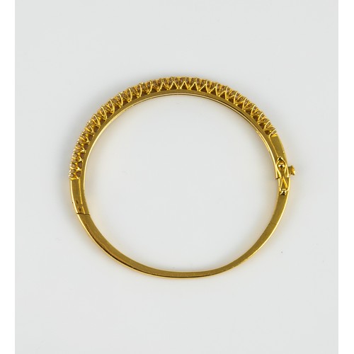 27 - GOLD AND DIAMOND HINGE-OPENING BANGLE, the top claw set with a half hoop of 26 round, brilliant cut ... 