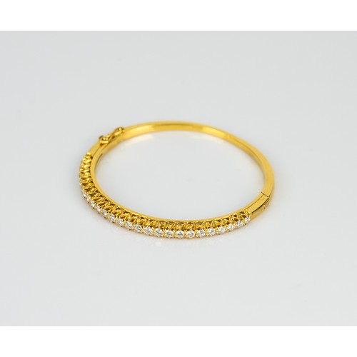 27 - GOLD AND DIAMOND HINGE-OPENING BANGLE, the top claw set with a half hoop of 26 round, brilliant cut ... 