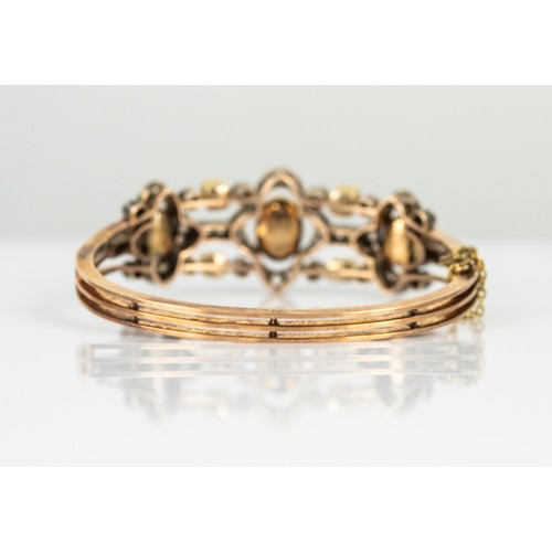 39 - EARLY 19th CENTURY GOLD AND WHITE GOLD TRIPLE STRAND HINGE-OPENING OVAL BANGLE, the top with 7 colle... 