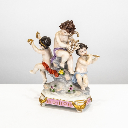 84 - LATE 19TH CENTURY GERMAN PORCELAIN GROUP OF THREE PUTTI MUSICIANS, all seated on a tree stump on a f... 