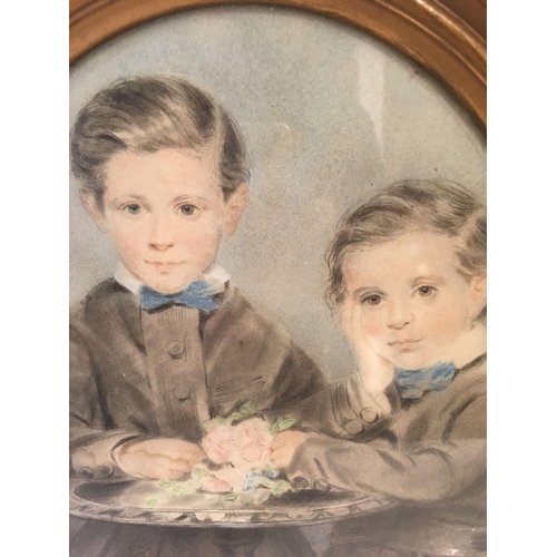 566 - AN OVAL 19THC PASTEL DRAWING. A PORTRAIT OF TWO YOUNG BOYS STOOD BY A SMALL 	ROUND TABLE,  OVAL,  7'... 