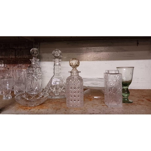 216 - 2 SHELVES OF DRINKING GLASSES, DECANTERS, GLASS CAKE DISH & OTHER GLASSWARE