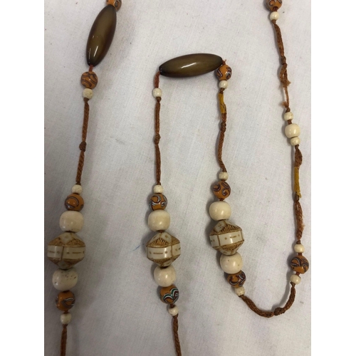 766 - AN ART DECO LONG NECKLACE WITH CARVED BONE, HANDMADE GLASS & HORN BEADS  THREADED ON SILK, & HUNG WI... 