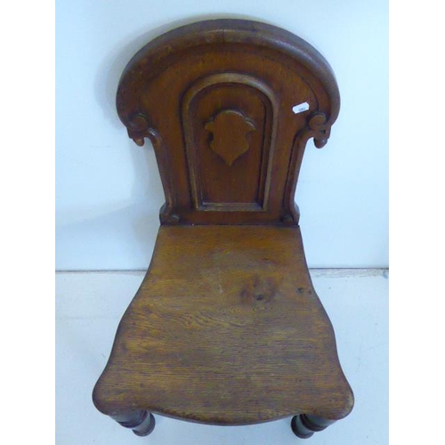 578 - A Victorian oak hall chair, the carved panelled back with swan neck pediment, solid seat and taperin... 