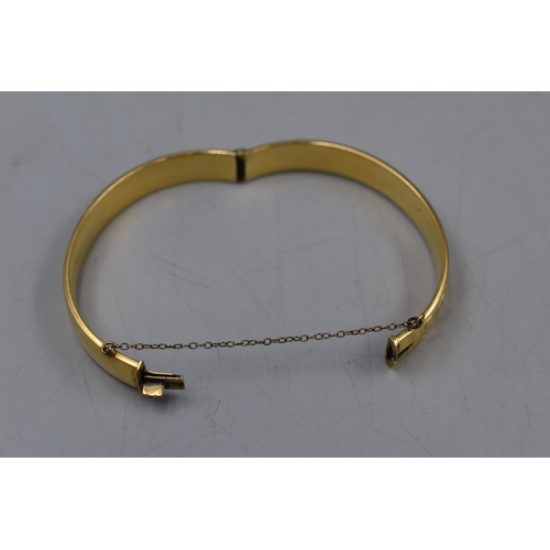 144 - A 9ct Rolled Gold Etched Bangle With Safety Chain.