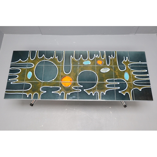 569 - A 1960s/70s polished metal coffee table, the rectangular top inset with a psychedelic abstract in co... 