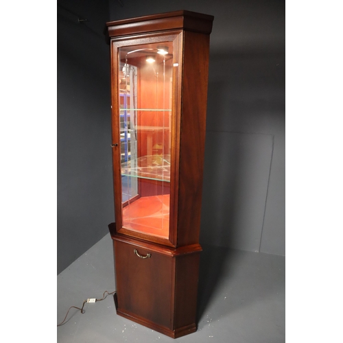 606 - An Illuminated Corner Display Unit. Glass Door, Two Glass Shelves and Mirrored Back, Over Wooden Doo... 