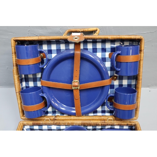 682 - Wicker four person picnic basket to include mugs, plates, bowls and cutlery.