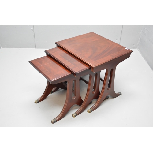 587 - Nest of three dark wood tables with brass claw feet, largest 21