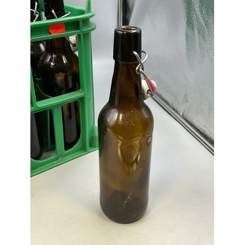 813 - Seventeen Brown Glass Swing Top Bottles, In Bottle Crate. Bottles Are Approx 26cm Tall