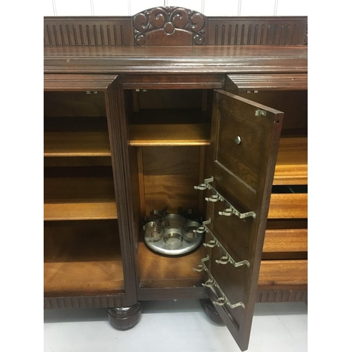 577 - A solid oak buffet-style sideboard/drinks cabinet.
Three brass-handled cupboards incorporating shelv... 