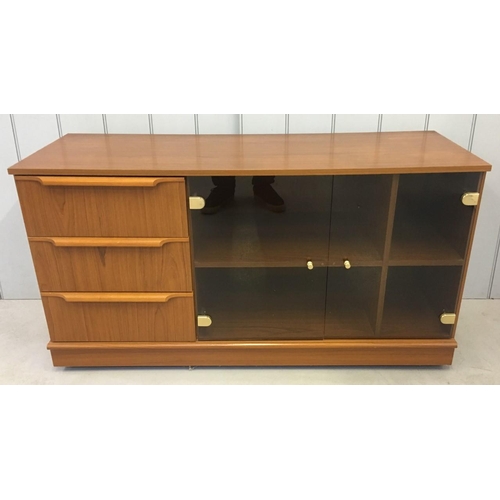118 - A mid-century, teak coloured TV/Hi-Fi Cabinet. Glass doored, two-shelved, three drawers, on castors.... 