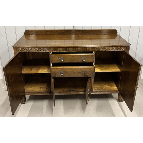 76 - An oak buffet sideboard.
Two door cupboard with central cutlery drawer & another, over a narrow cupb... 