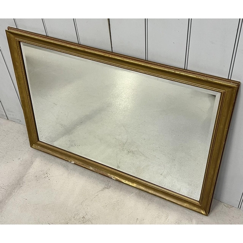 255 - A gold coloured overmantle mirror, with bevelled edge. 70cm x 99cm.