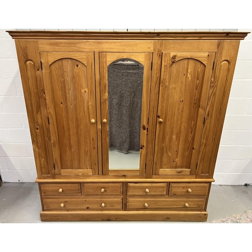 53 - A stunning, solid pine triple wardrobe. Wardrobe sits upon a base of six drawers. Central mirrored d... 