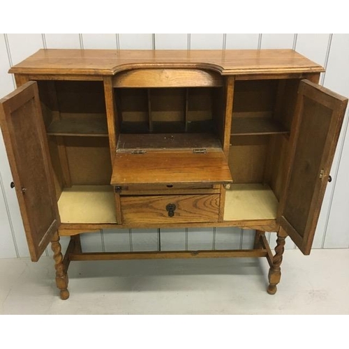 108 - An Edwardian oak bureau. Twin cupboards aside fall front desk area & two drawers. Stretchered suppor... 