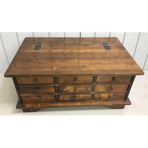 11 - A contemporary Sheesham wood coffee table, having hinged half lid over a set of nine apothecary styl... 