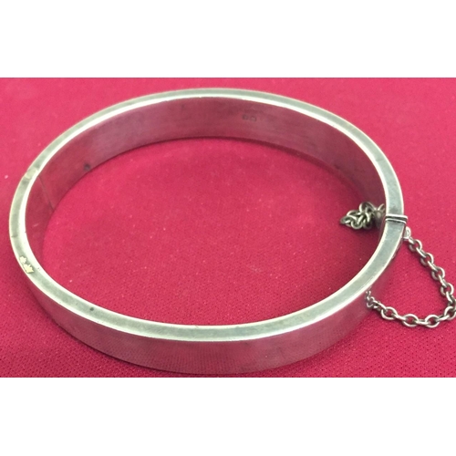 409 - A hallmarked, sterling silver bangle, with safety chain. Weight approx. 20g.