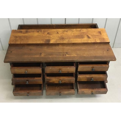 11 - A contemporary Sheesham wood coffee table, having hinged half lid over a set of nine apothecary styl... 