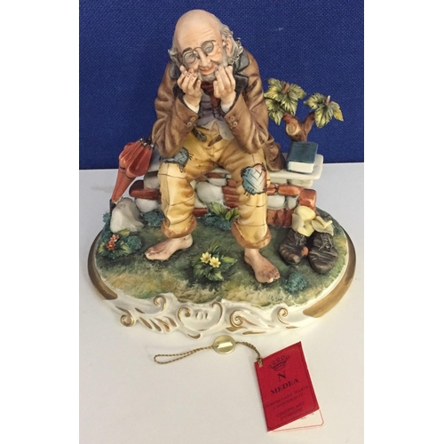 573 - A Capodimonte figurine, depicting an old man on bench. Height 24cm.