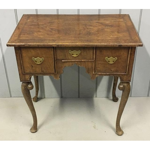 61 - A Georgian walnut lowboy, with three short brass-handled drawers, over a shaped apron, on cabriole l...