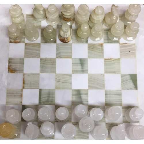 761 - A marble chess board, together with onyx/marble pieces.