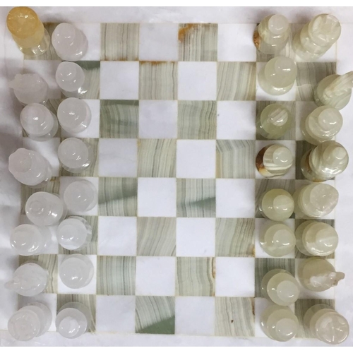 761 - A marble chess board, together with onyx/marble pieces.