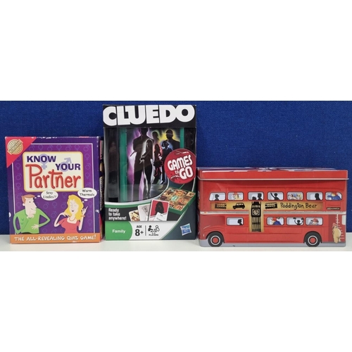 766 - Two boxed 'Games to Go Cluedo' & 'Know Your Partner', together with a 'Paddington' tin.