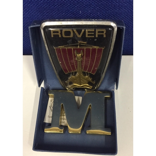 688 - A boxed, solid brass paperweight initial 'M', together with a vintage Rover car emblem.