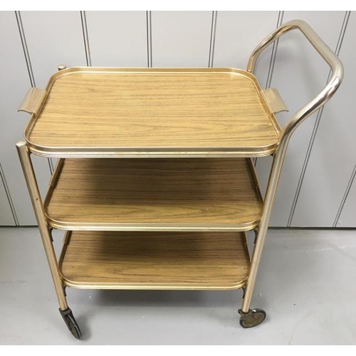 128 - A vintage, gold-coloured tea trolley, with three shelves, together with a similar-styled tray. Dimen... 