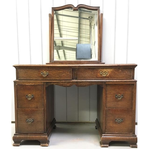 64 - An Edwardian oak dressing table. Two shallow & four deep drawers. Tilting mirror (mirror requires wi... 