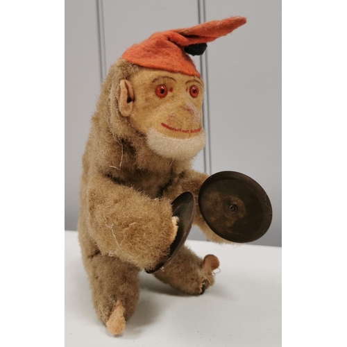 A vintage, likely West German, clockwork cymbal-playing monkey from 1950's. Height approx. 16cm. Shows signs of playwear. Key present. Winds with intermittent working.