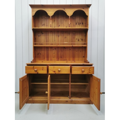 1003 - A solid pine Welsh dresser. Upper level houses two plate-rack shelves, over a triple cupboard/drawer... 