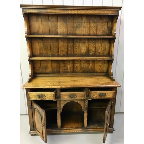 29 - A dark oak Welsh dresser, with two plate shelves, three drawers & double cupboard aside arched reces... 