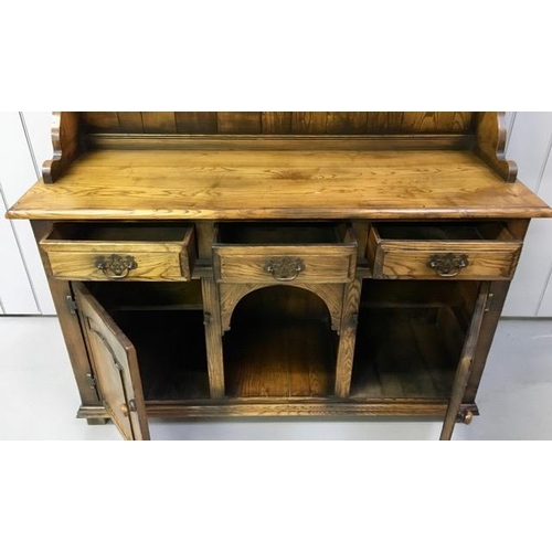 29 - A dark oak Welsh dresser, with two plate shelves, three drawers & double cupboard aside arched reces... 