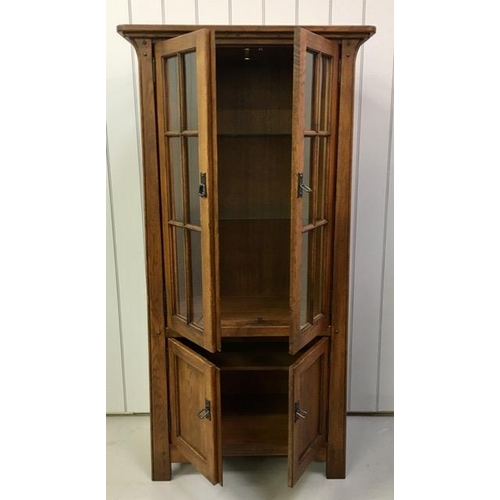 52 - An oak corner display cabinet, with two glass shelves & a single shelved cupboard. PAT test pass & l... 