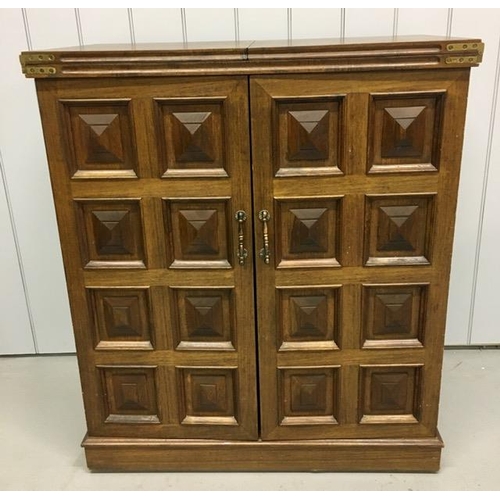 53 - A solid oak/panelled, metamorphic drinks bar. Features hinged opening glass holders & a hinged, exte... 