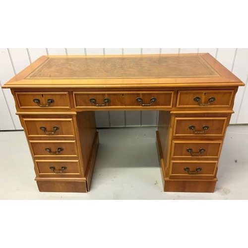 72 - A yew-veneered pedestal desk, with nine drawers. No key present. Left hand pedestal plinth will need... 