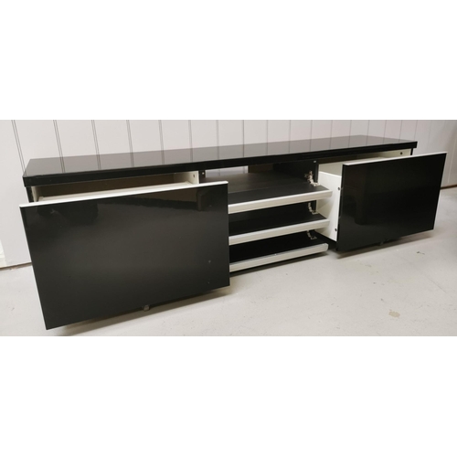 112 - A large, contemporary TV cabinet/media organiser, in gloss black. Features three fall-front central ... 